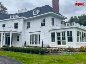A large white house with a new roof and sunroom, showcasing exterior renovation by Mendez Contractor Inc in Lynn, MA
