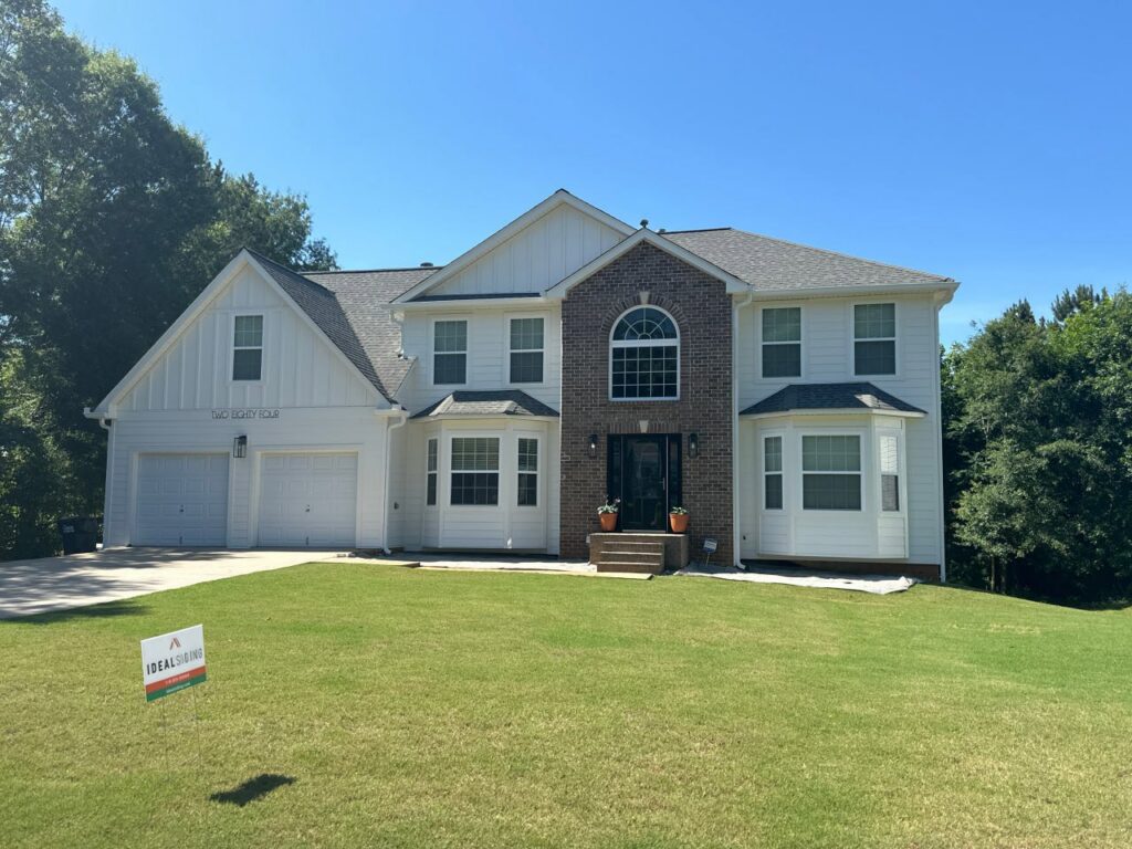 A grand white house with new siding and brick accents, showcasing a completed exterior by Ideal Siding Richmond, VA.