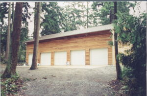 A large, newly built garage with wood siding and multiple white garage doors by Garages Etc in Tacoma, WA