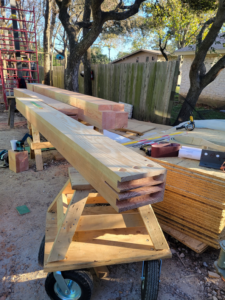 Large wooden beams and construction materials on a job site, prepared by Hill Country Framing in Austin, TX
