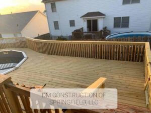 A large, newly built wooden deck surrounding an above-ground swimming pool, by DM Construction of Springfield in Springfield, IL.