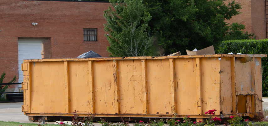 A large yellow dumpster partially filled with debris, ready for junk removal by Massie Dumpster Rental in Las Vegas, NV.