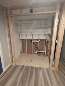 A laundry area with exposed wood framing and plumbing during renovation by Asbestos Abatement, Inc in Englewood, CO.