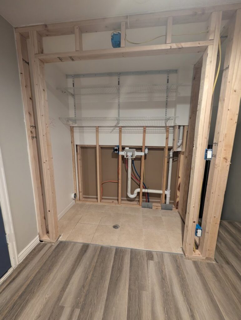 A laundry area with exposed wood framing and plumbing during renovation by Asbestos Abatement, Inc in Englewood, CO.