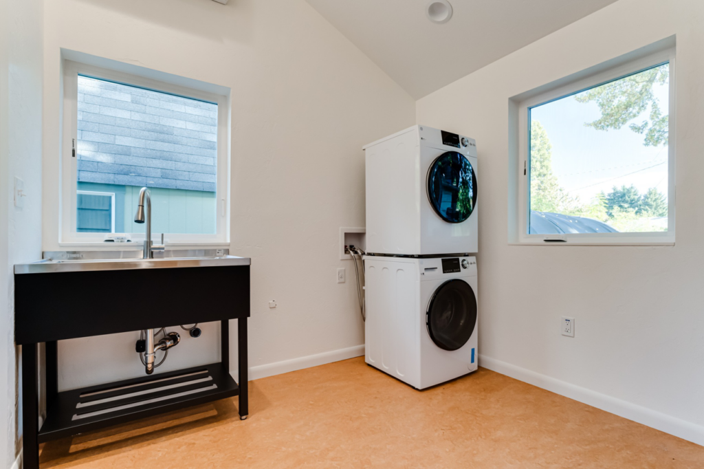 A laundry room featuring a stacked washer and dryer and a utility sink installed by Matt Bennett Construction in Junction City, OR