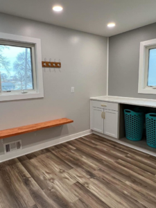Floating wooden bench and coat hooks installed in a renovated laundry room by SMB Construction in Toledo, OH.
