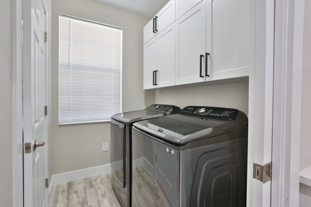 A laundry room with newly installed white cabinets and appliances by ALKA Construction/ Handyman Services in Layton, UT