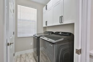 A laundry room with newly installed white cabinets and appliances by ALKA Construction/ Handyman Services in Layton, UT