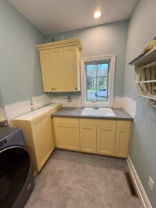 A laundry room with new cabinets and sink installed, showing renovation work by Hawk Handyman Services in West Fargo, ND