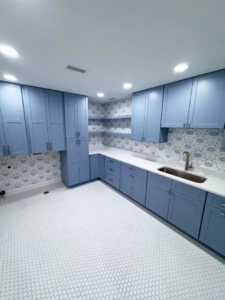 A renovated laundry room with blue cabinets, white countertops, and a sink installed by Shipe Builders in Salisbury, MD.
