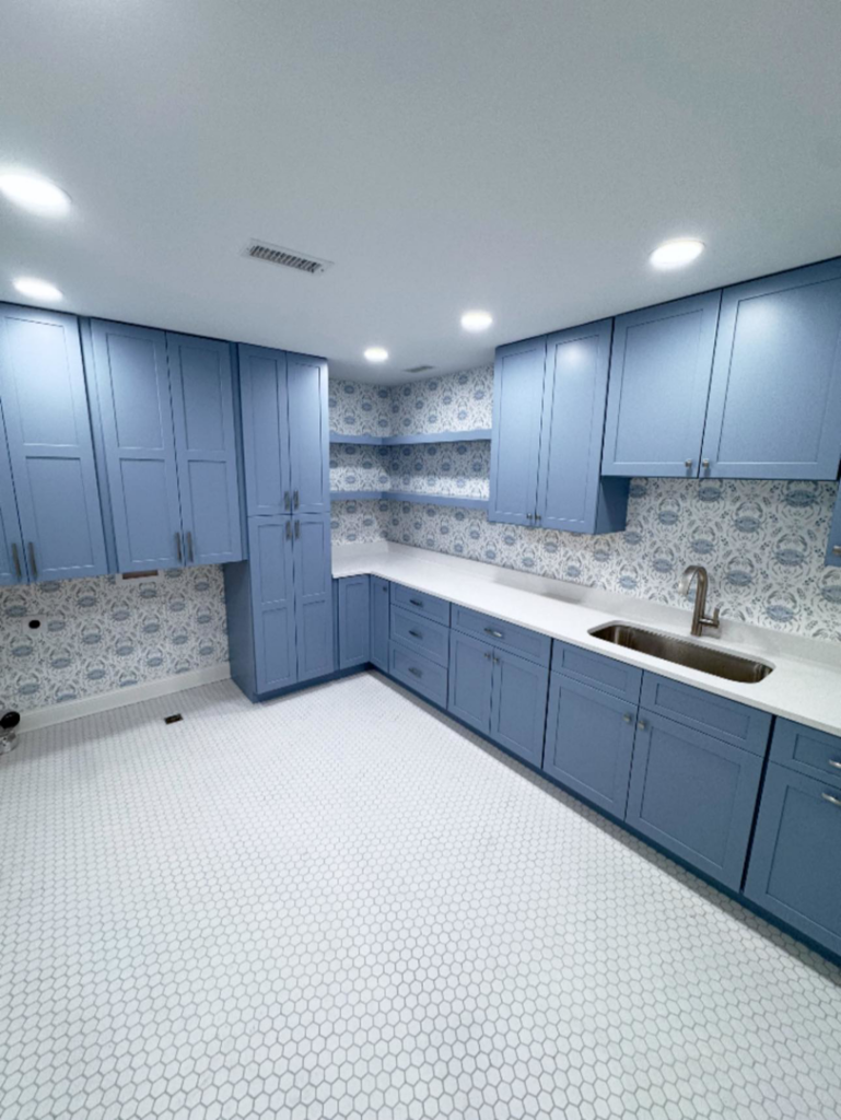 A renovated laundry room with blue cabinets, white countertops, and a sink installed by Shipe Builders in Salisbury, MD.
