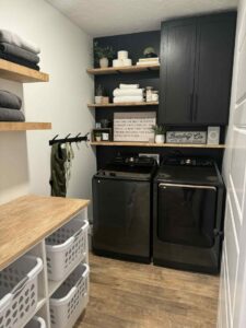 A renovated laundry room with custom floating shelves and black cabinets installed by Renegade Woodworks in Kearney, NE.