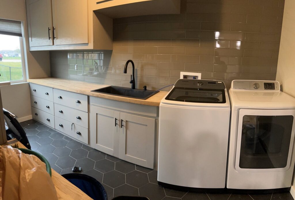 A remodeled laundry room featuring a new sink, countertop, custom cabinets, and appliances by The Sioux Falls Handyman in Sioux Falls, SD.