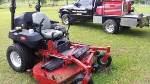 A large red lawnmower next to a service truck for Tim's Maintenance & Repair in Las Vegas, NV, ready for equipment repair