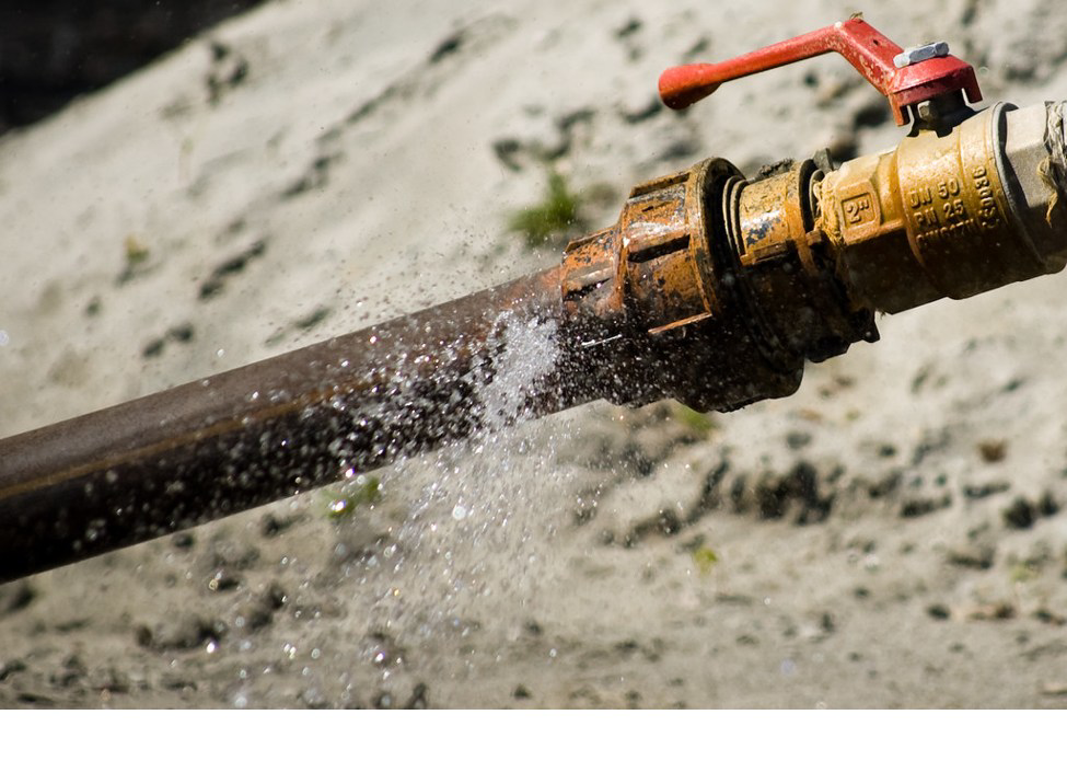 A rusty, leaking pipe with a red valve, showing a plumbing repair job by Quality Home Services in Fresno, CA.
