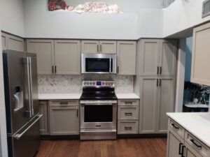A renovated kitchen with light brown cabinets, stainless steel appliances, and a decorative backsplash by Camelback Cabinets in Gilbert, AZ