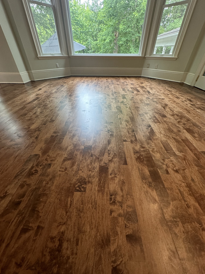 A gleaming light brown wood floor in a bright room, showcasing work by SANDMAN WOOD FLOOR REFINISHING in Cleveland, OH.