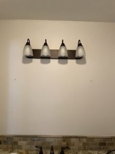 Wall showing mounting holes where a light fixture was removed, indicating preparation for a new installation by Absolute Integrity Handyman Services Inc in Fresno, CA.