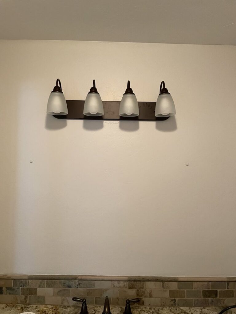 Wall showing mounting holes where a light fixture was removed, indicating preparation for a new installation by Absolute Integrity Handyman Services Inc in Fresno, CA.
