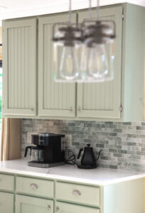 Detail of light green kitchen cabinets and a stylish backsplash, part of a remodel by DeShong Design + Remodeling in Pittsburgh, PA.