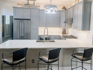 A kitchen remodel with light grey cabinets, white subway tile backsplash, and stainless steel appliances by CMT Construction LLC in Columbia, MO.