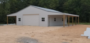 A light grey metal garage with a white garage door and two attached carports, built by D.H. Construction in Jackson, TN.