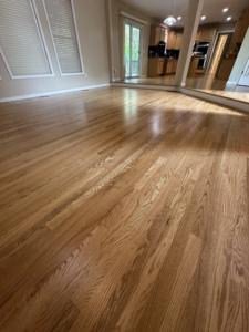 A bright, light wood floor connecting an open living and kitchen area, refinished by SANDMAN WOOD FLOOR REFINISHING in Cleveland, OH.