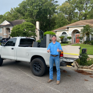 A Litter Hitters employee giving a thumbs up next to a pickup truck loaded with junk after a successful removal job in Jacksonville, FL.