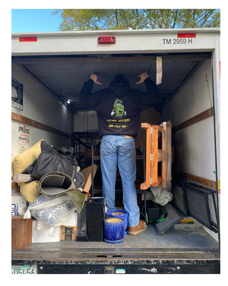 A Litter Hitters junk removal truck fully loaded with various household items and debris in Jacksonville, FL.