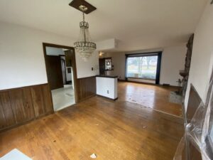 A living and dining area before renovation, showing old wood paneling and flooring by RT Property Services in Allendale, MI