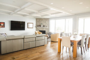 An open-concept living and dining area remodel featuring a coffered ceiling and fireplace by Knaub Home Solutions in Rochester, NY.