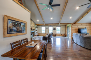 A renovated living and dining room featuring wooden floors and a stone fireplace by GCU Custom Builders in Louisville, KY.