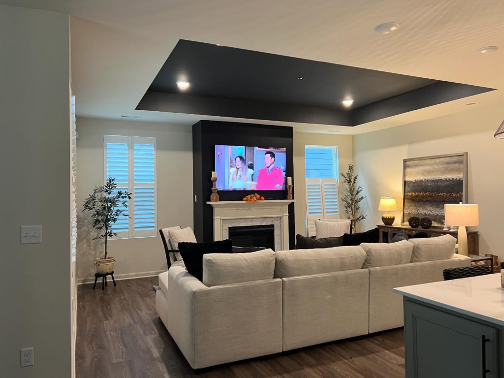 A modern living room featuring a dark accent ceiling and fireplace wall by Wilder Painting, LLC in Quincy, MA