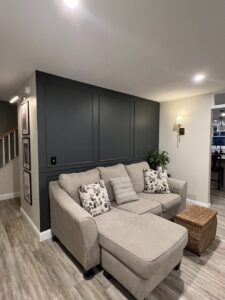 A living room with a newly installed dark accent wall featuring decorative paneling, completed by Sini's Handyman Services in Falmouth, ME.