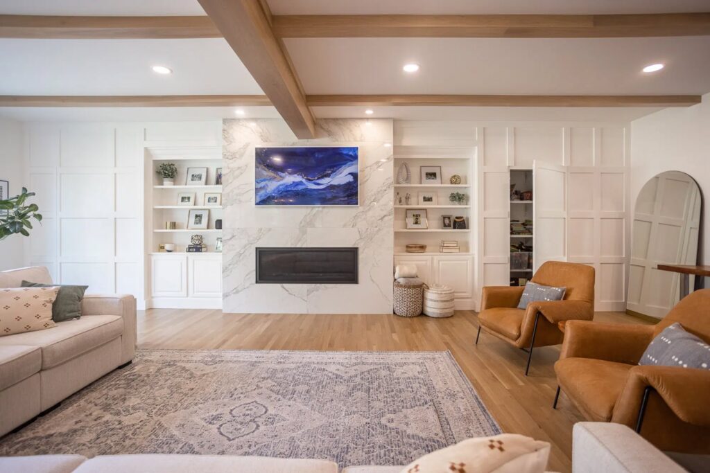 A living room featuring custom built-in shelving, a modern fireplace, and decorative wood beams by Legacy Builders Group in Cincinnati, OH.