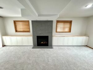 A renovated living room featuring built-in white cabinets and a modern fireplace by Northeast SD Handyman in Watertown, SD.