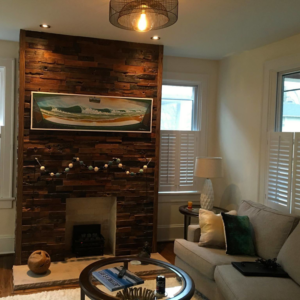 A beautifully renovated living room featuring a wood-paneled fireplace accent wall by Serene Construction, LLC in Richmond, VA.