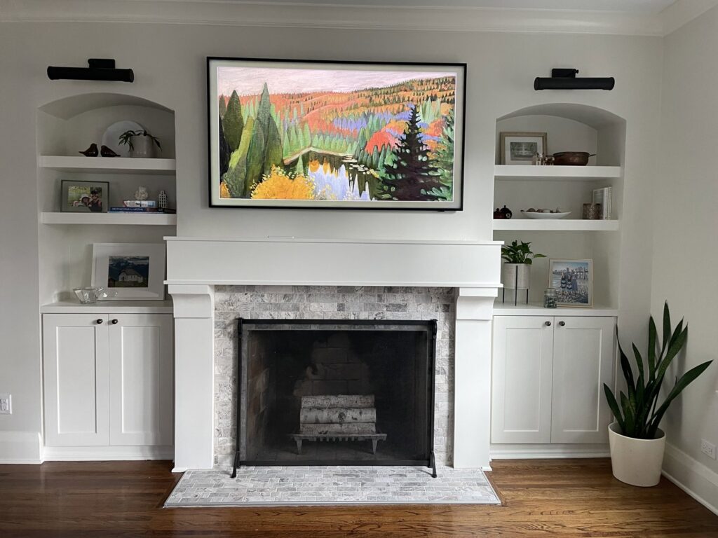 A renovated living room featuring a modern fireplace with stone surround and custom white built-in shelves by Inova Builds in Bloomington, MN.