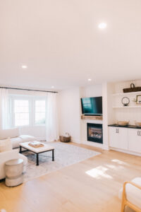 A renovated living room featuring a modern fireplace, custom built-in shelves, and hardwood floors by Knaub Home Solutions in Rochester, NY.