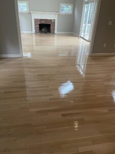 Living room with a brick fireplace and newly finished hardwood floor by Diamond Flooring LLC in Boston, MA