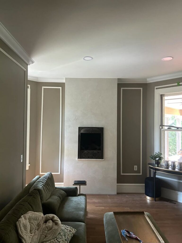 A living room featuring a fireplace and newly painted walls with decorative trim by Tribute Painting & Drywall in St. Louis, MO.