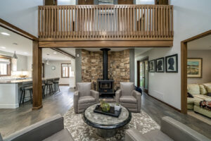 A remodeled living room featuring a stone fireplace and a wooden balcony by Saunders Dynamic Remodeling in Columbus, OH