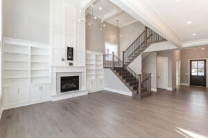 A spacious living room featuring a fireplace, built-in shelving, and a grand staircase by DJK Custom Homes in Naperville, IL