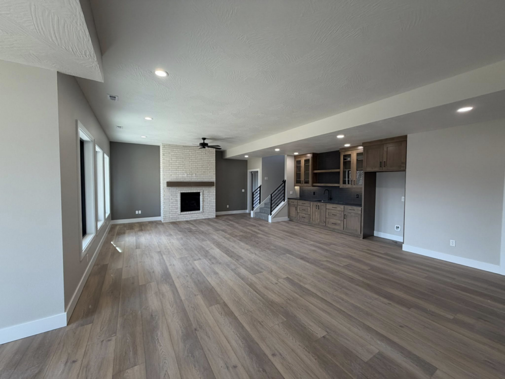 An open living space with a white brick fireplace and a custom wet bar by ELS Construction in Springfield, MO.