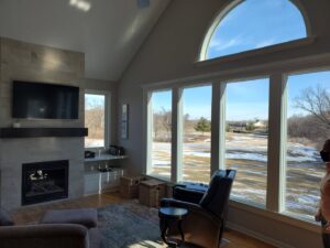 A modern living room with a new fireplace surround and large windows, completed by Affordable Granite of KC in Kansas City, MO.