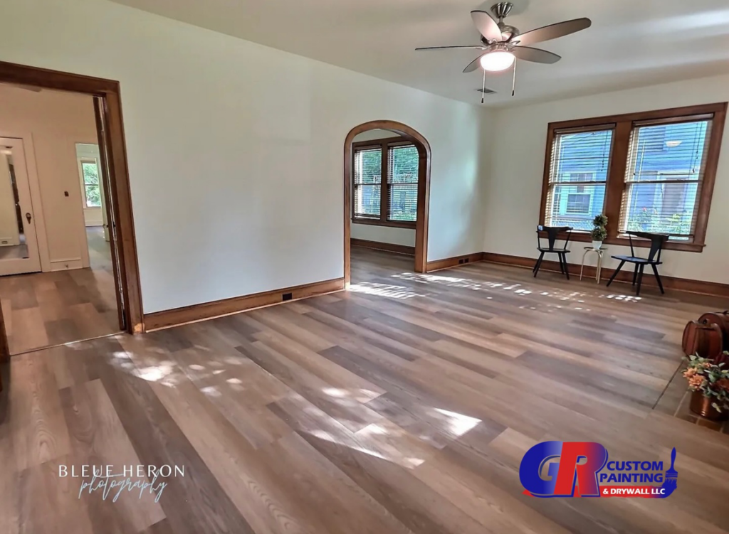A newly renovated living room featuring fresh paint and new wood-look flooring by GR Custom Painting & Drywall LLC in Shreveport, LA.