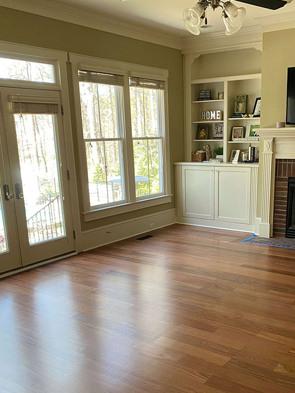 A renovated living room showcasing new hardwood floors and custom built-in shelving next to a fireplace by Falls Contracting, LLC in Raleigh, NC.