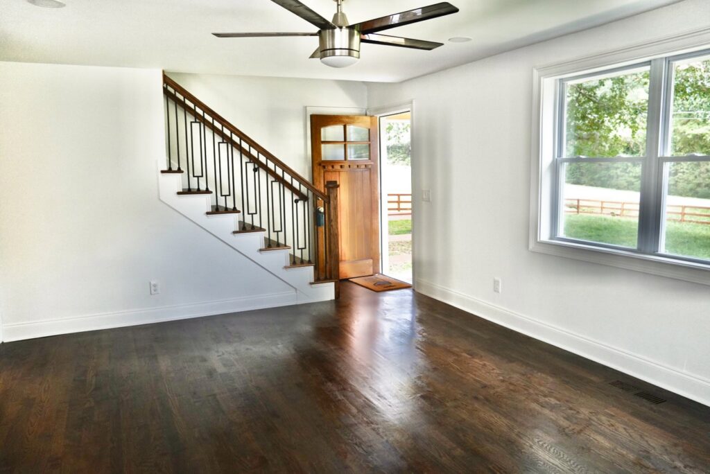 A living room with newly installed dark hardwood floors and matching stairs by Glenni Floors LLC in Roswell, GA.
