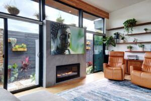 A contemporary living room featuring a modern fireplace and large windows overlooking a garden by Transformations Custom Build in Austin, TX