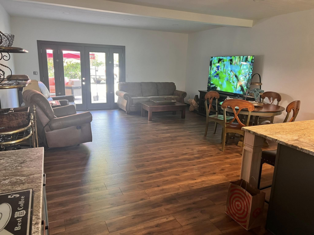 A living room with newly installed hardwood flooring and patio doors by One Up construction llc in Springfield, OR.
